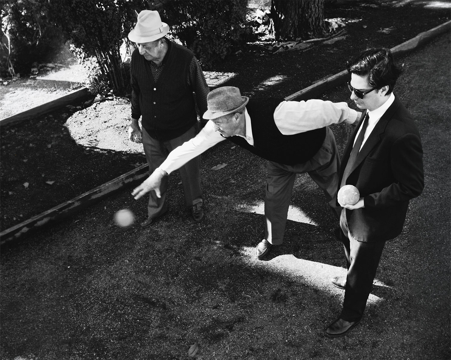 Three men playing bocce outdoors in black and white